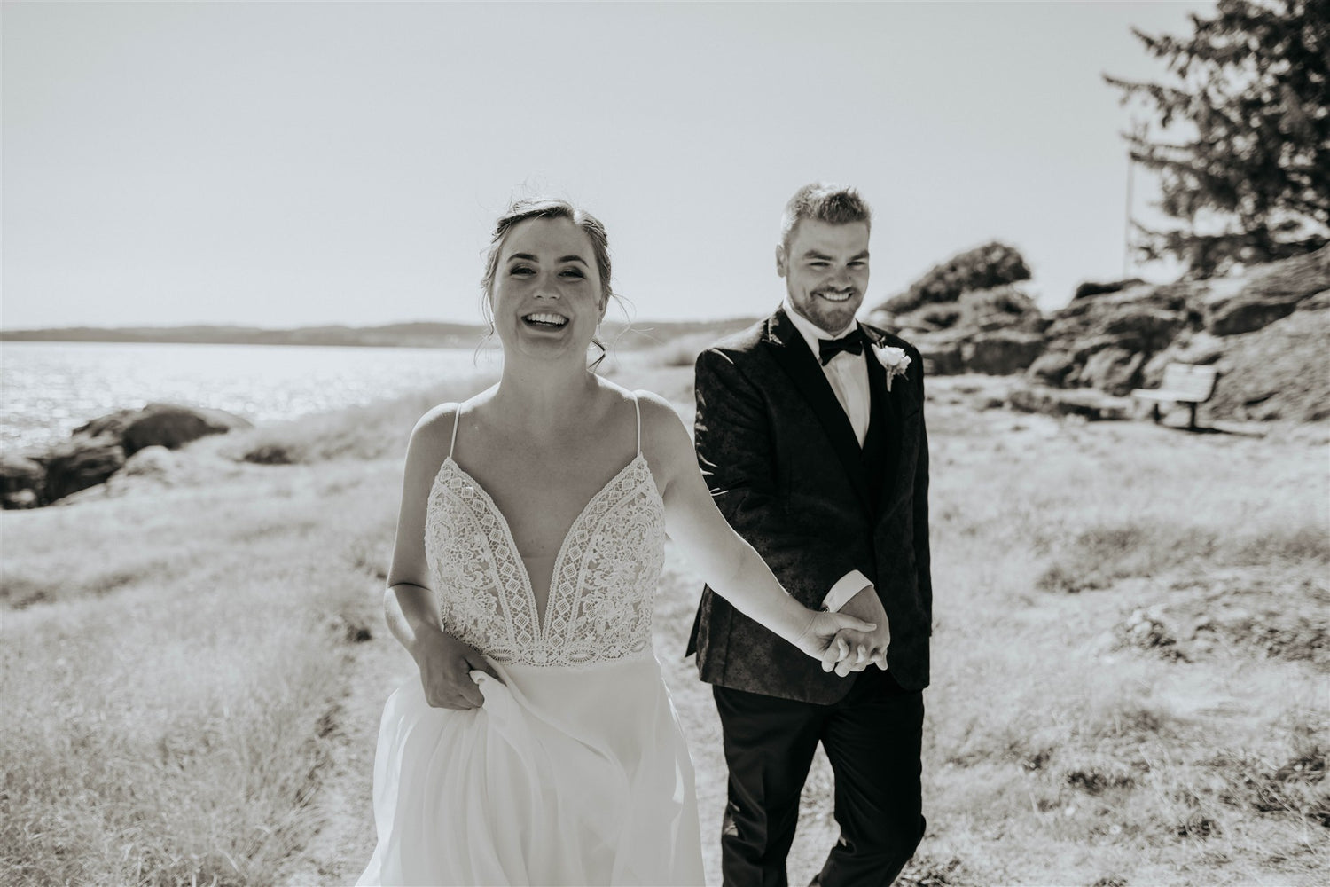 bride and groom holding hands and walking towards the camera along the ocean