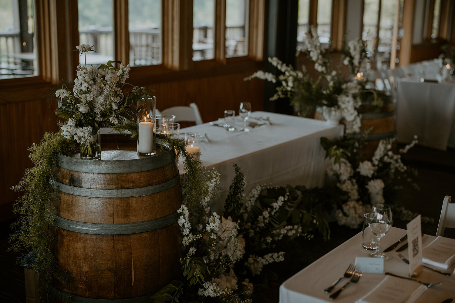 Sweetheart table surrounded by greenery and white florals in moody lighting. M and E's moody wedding at Church and State Wines, Isle + Oak Photography