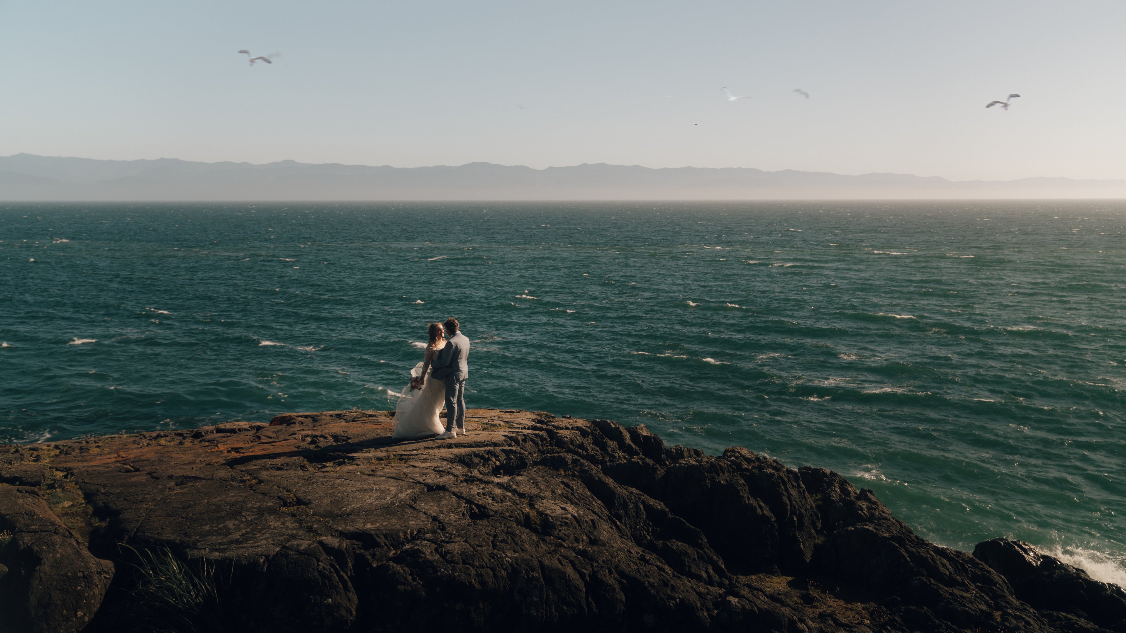 Bride and groom standing on a rock in front of the ocean. Vancouver Island wedding, Victoria BC Wedding, Taylor Dawning Photography