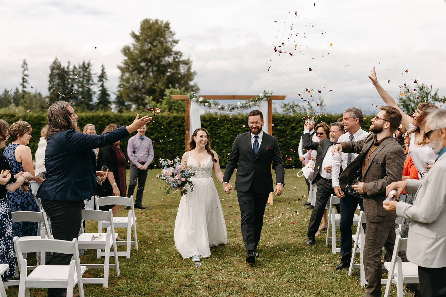 bride and groom walking back down the aisle with guests throwing flower petals