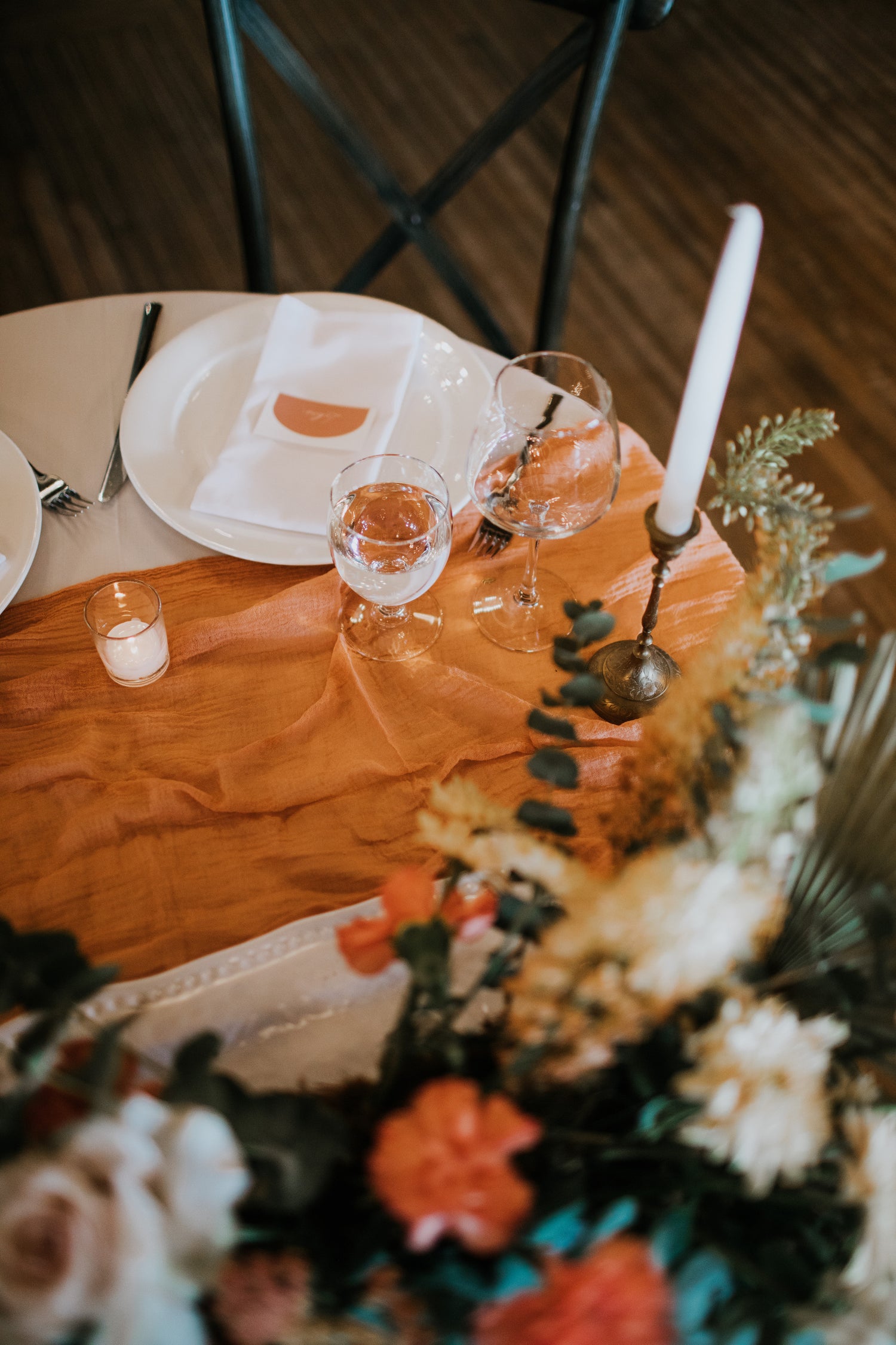 a close up image of a sweetheart table with a burnt orange table runner and tall candles